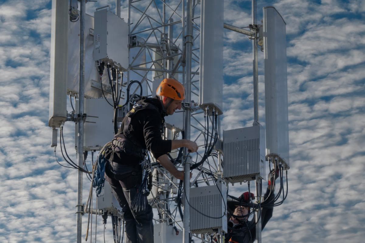 Dos técnicos instalando antenas en una torre de telecomunicaciones